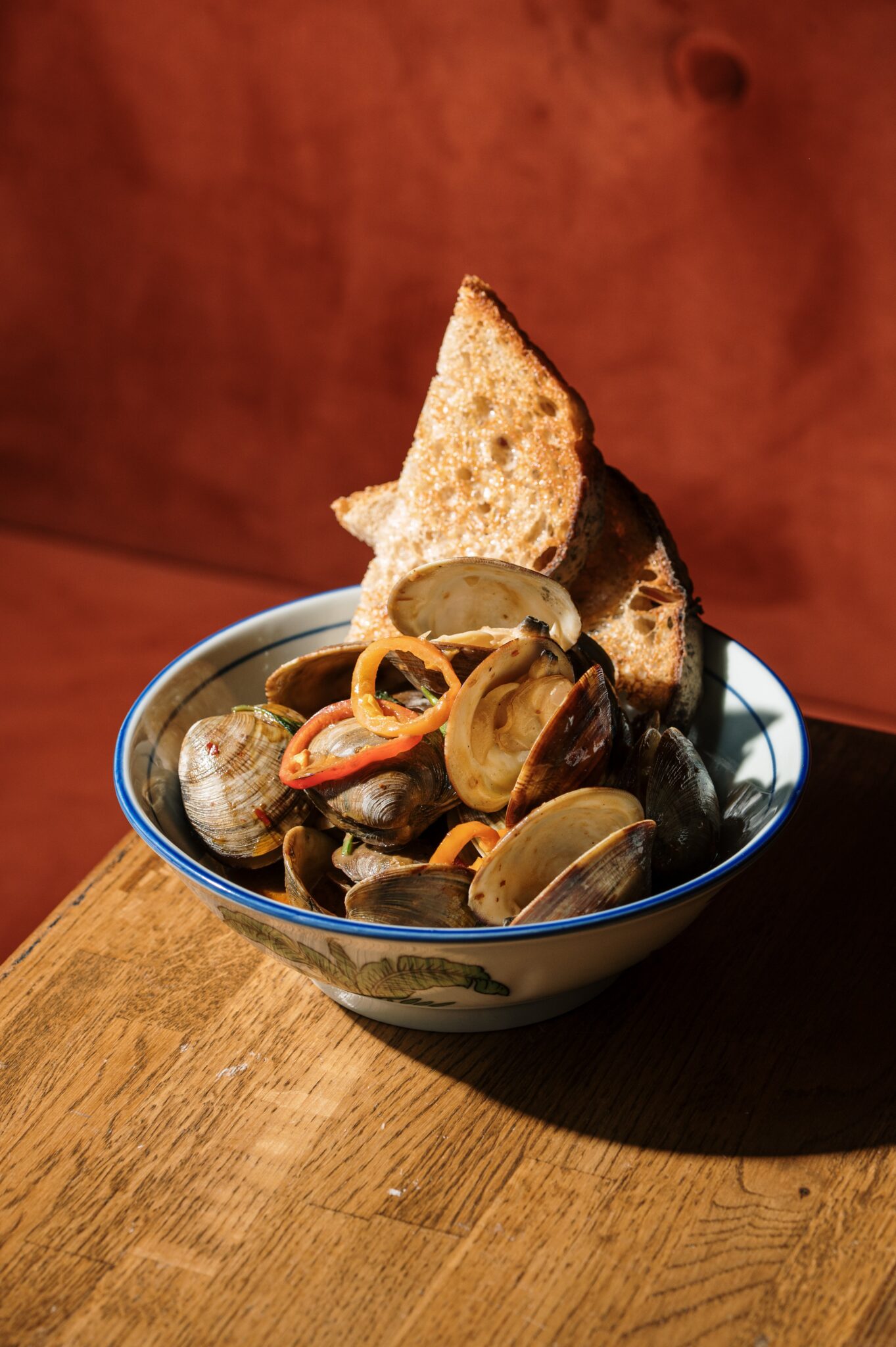 Steamed clams with a crisp flatbread wedge in a blue-rimmed bowl at Tipsy Thaiger in Roswell