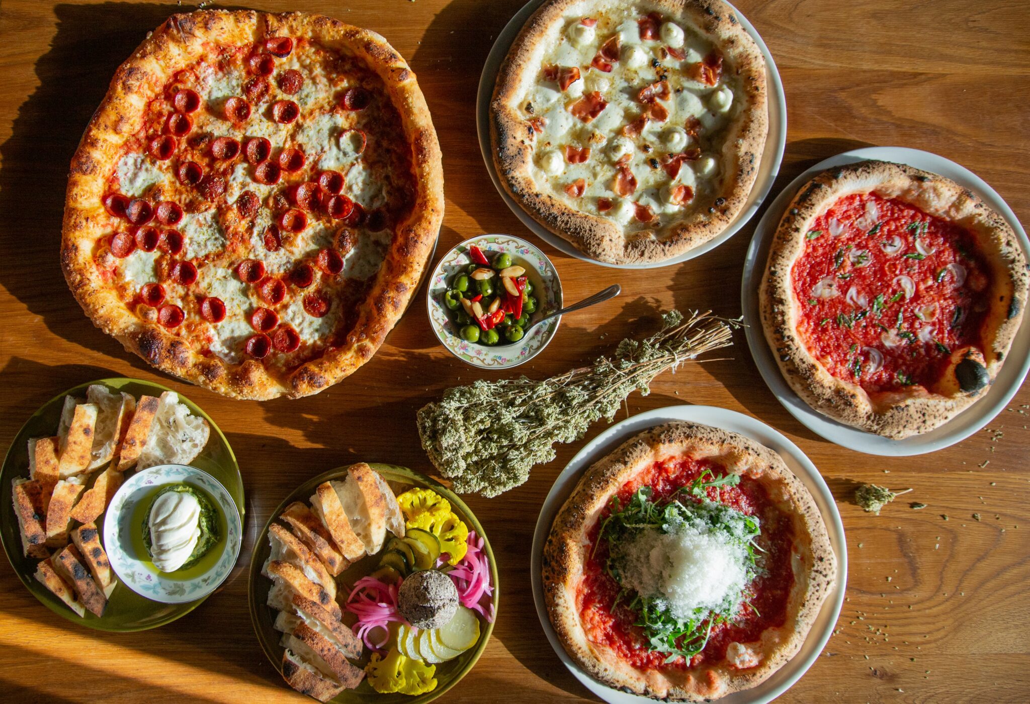 An overhead spread of pizzas and shared small plates at A Dopo in Knoxville, Tennessee