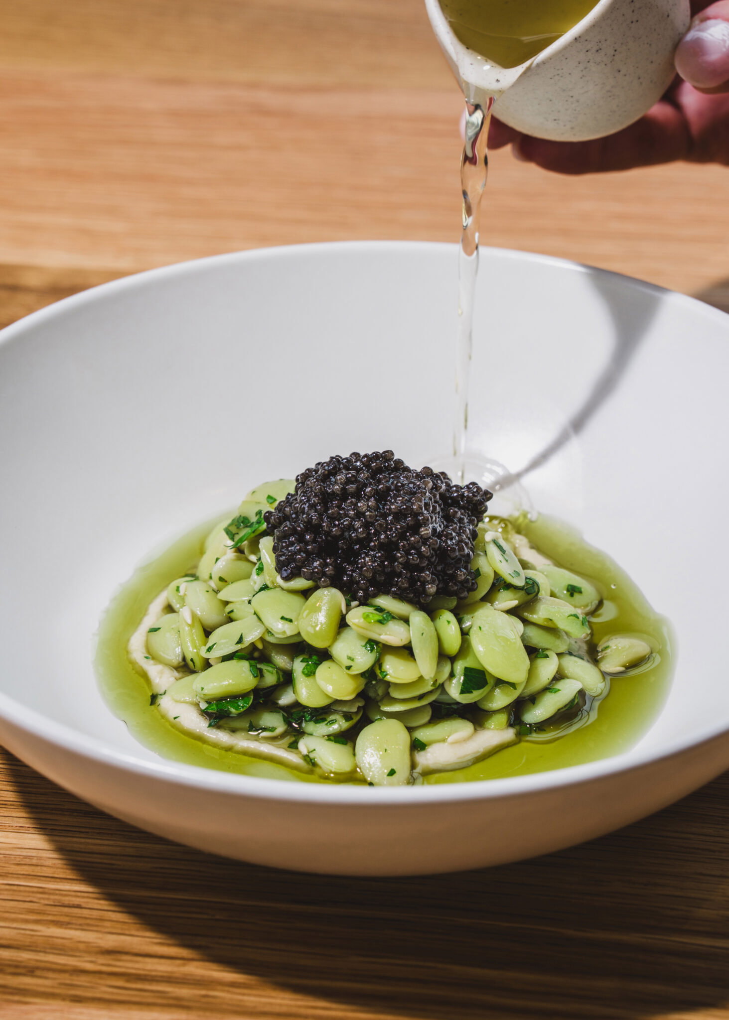 Broth poured over a bowl of green beans topped with a dark garnish at So. Fox in Atlanta