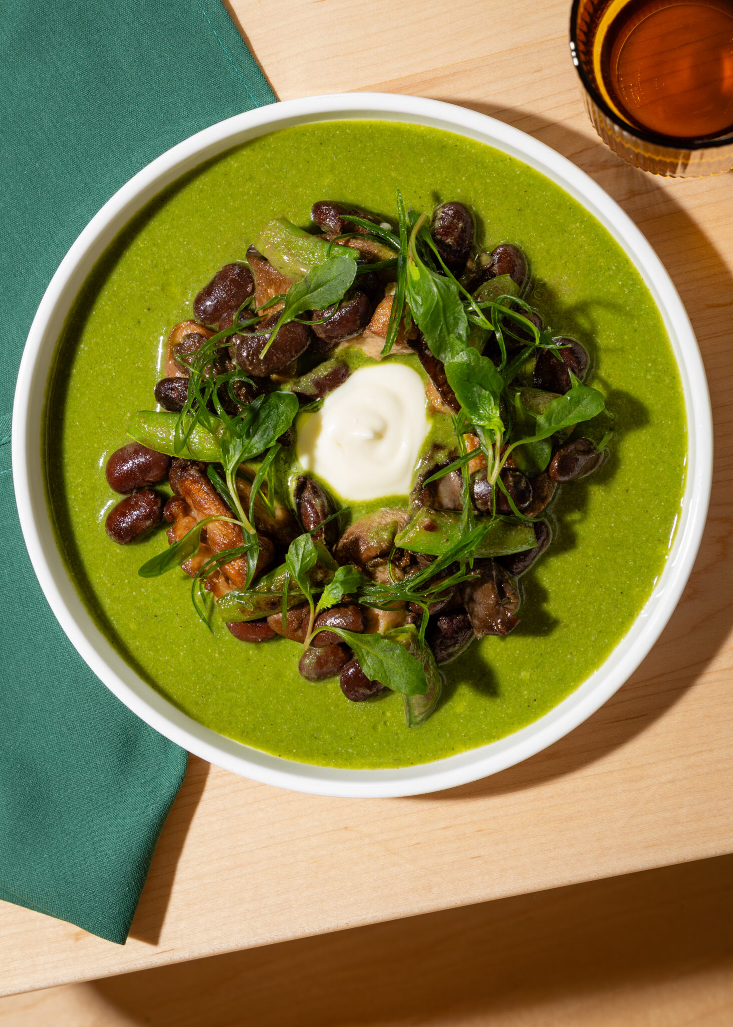A vibrant green mole with greens and crema in a white bowl at Maiz De La Vida in Nashville