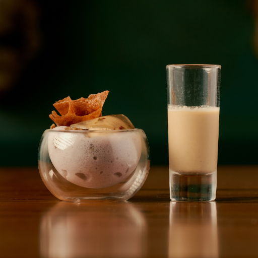 A layered dessert in a glass beside a tall glass of a creamy drink at Dakar NOLA