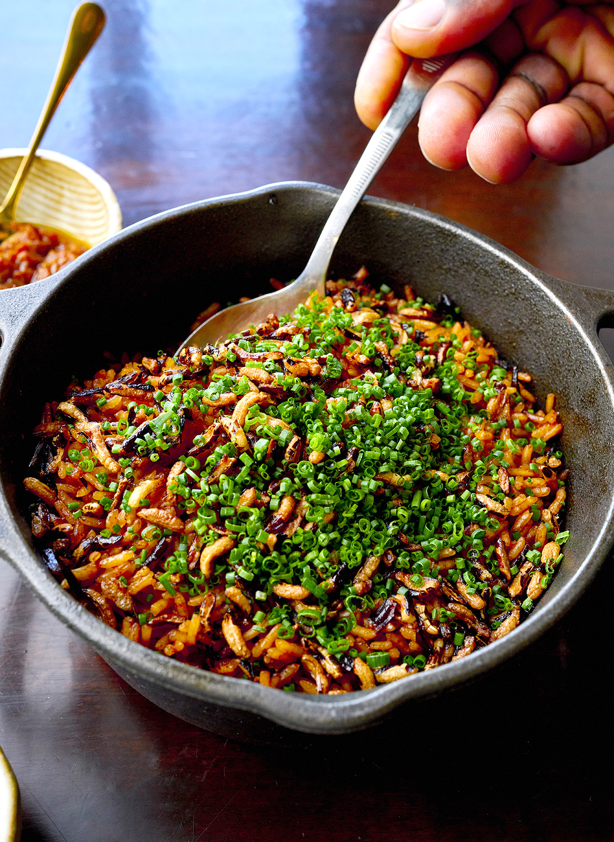 Jollof rice topped with herbs in a cast-iron pan at Dakar NOLA in New Orleans