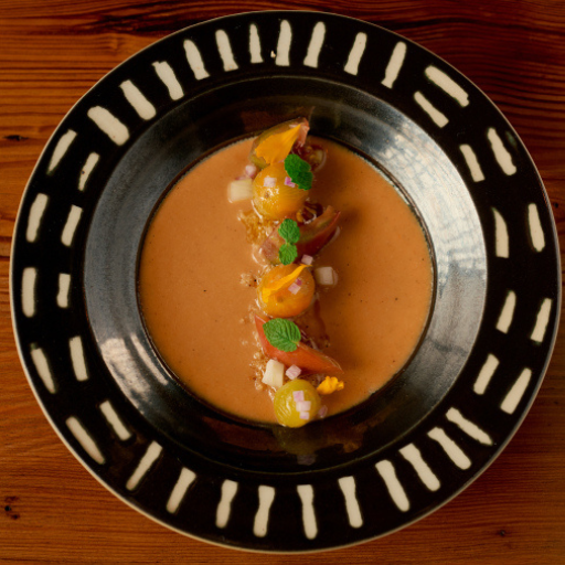 A seafood course in a rich broth on a black-and-white patterned plate at Dakar NOLA