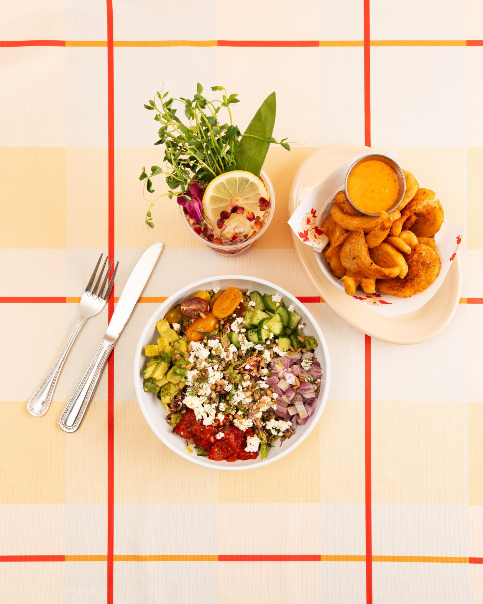 Colorful salads and small plates on a striped tablecloth at Safta’s Table in New Orleans