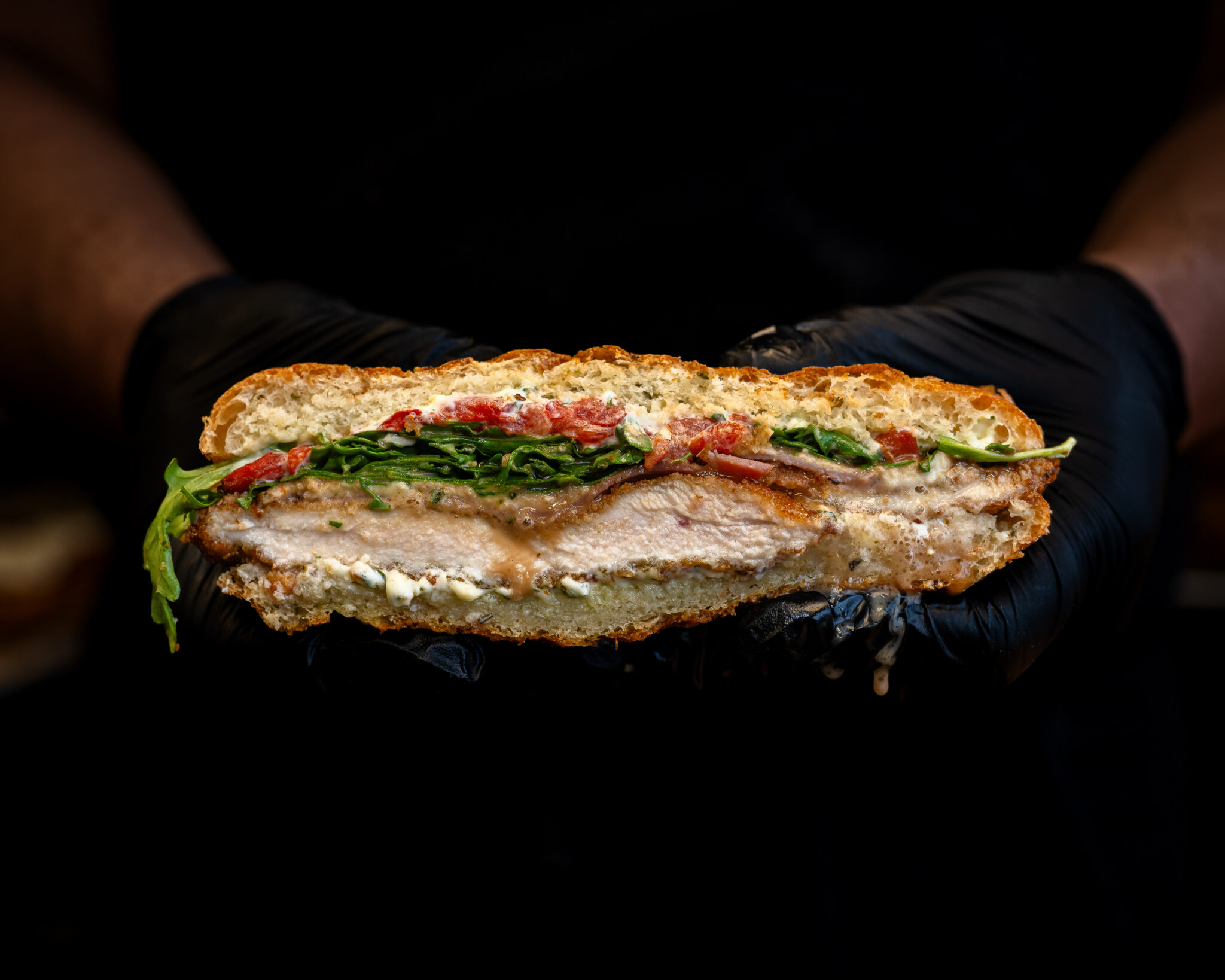 A sandwich held in gloved hands at Ideal’s in Durham, North Carolina