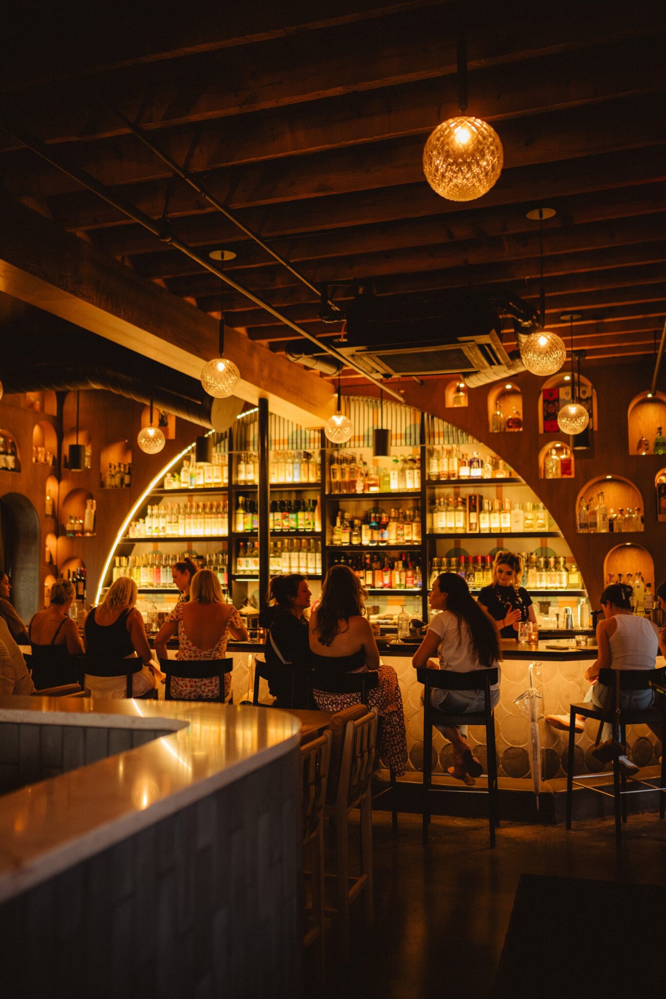 The arched back bar glowing with pendant lights at The Story of Mi Cariño in Charlotte