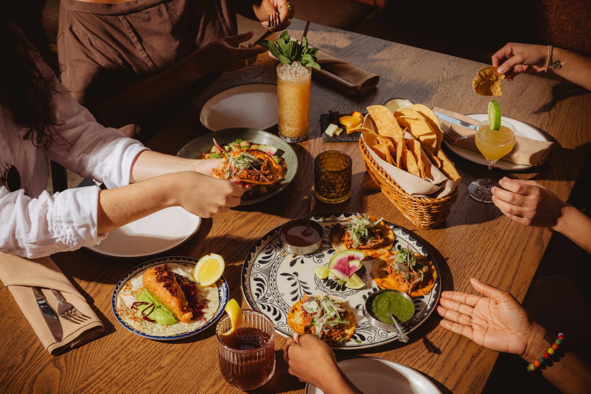 Guests sharing plates and drinks around a table at The Story of Mi Cariño in Charlotte