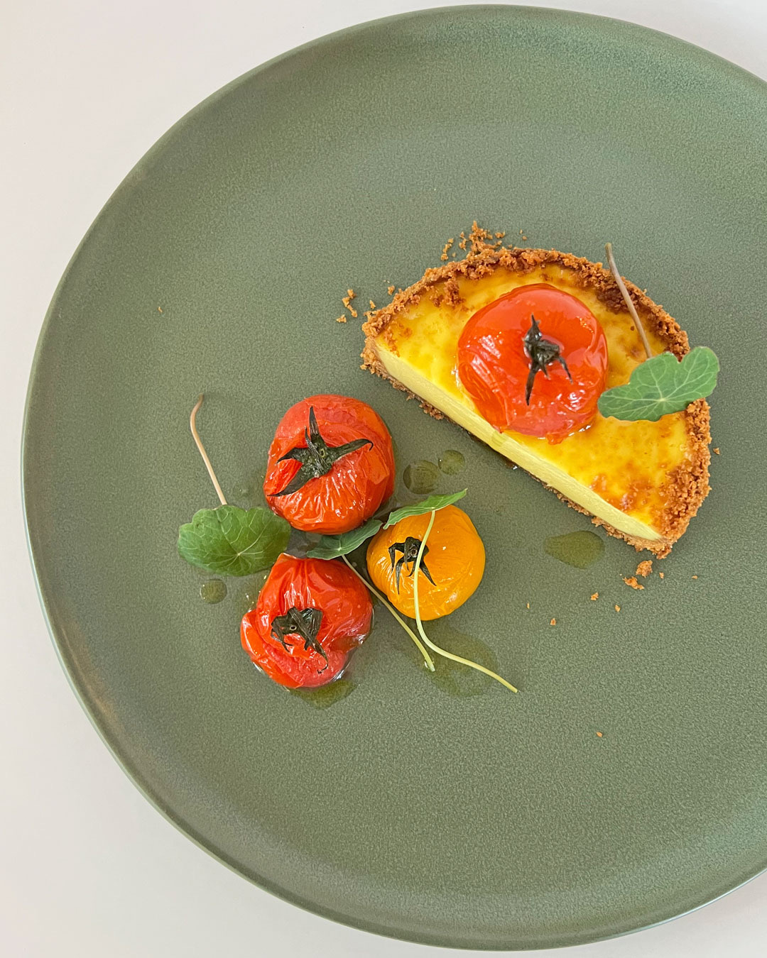 A tomato tart slice with roasted tomatoes on a sage green plate at Summerland in Atlanta