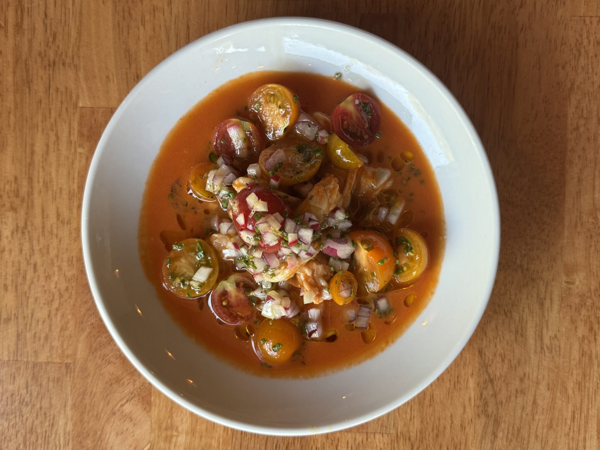 A brothy soup with diced vegetables in a white bowl at Tesoro in Carrboro, North Carolina