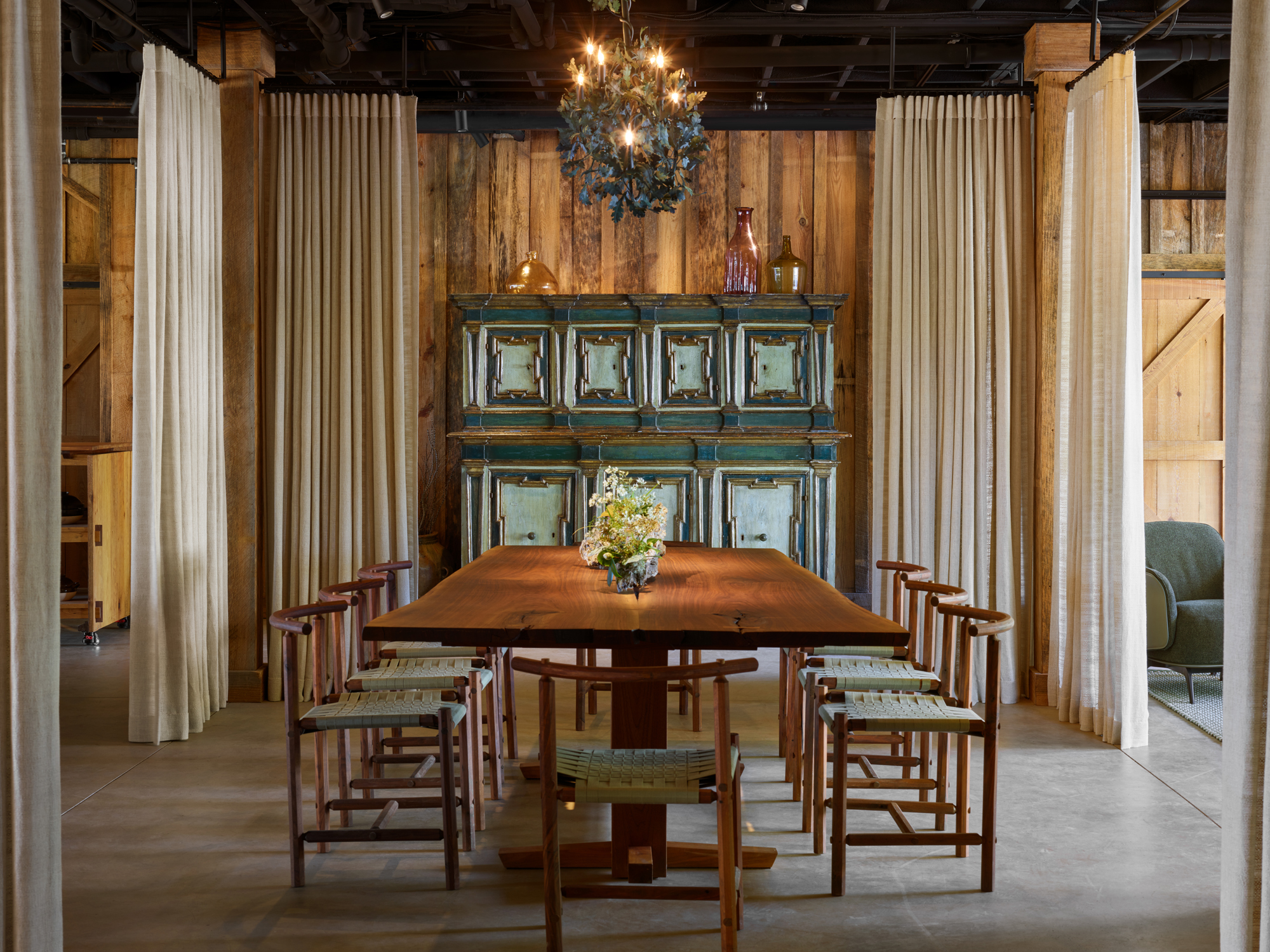 The candlelit dining room at Uberto Restaurant with a long wooden table and draped walls