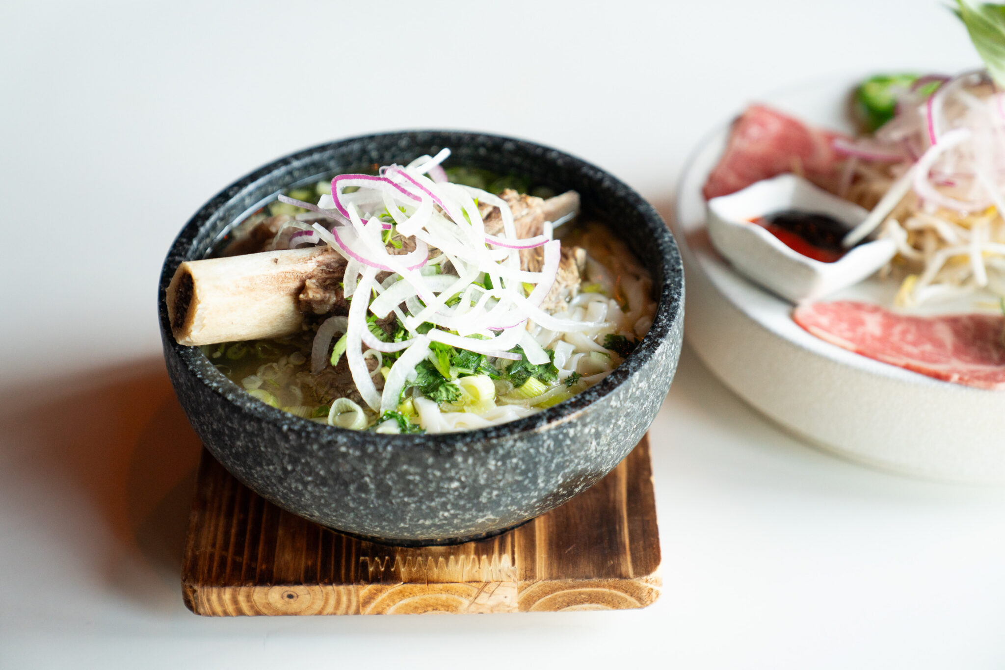 A bowl of pho with fresh herbs and sliced beef at Bao Toan Kitchen & Bar in Memphis