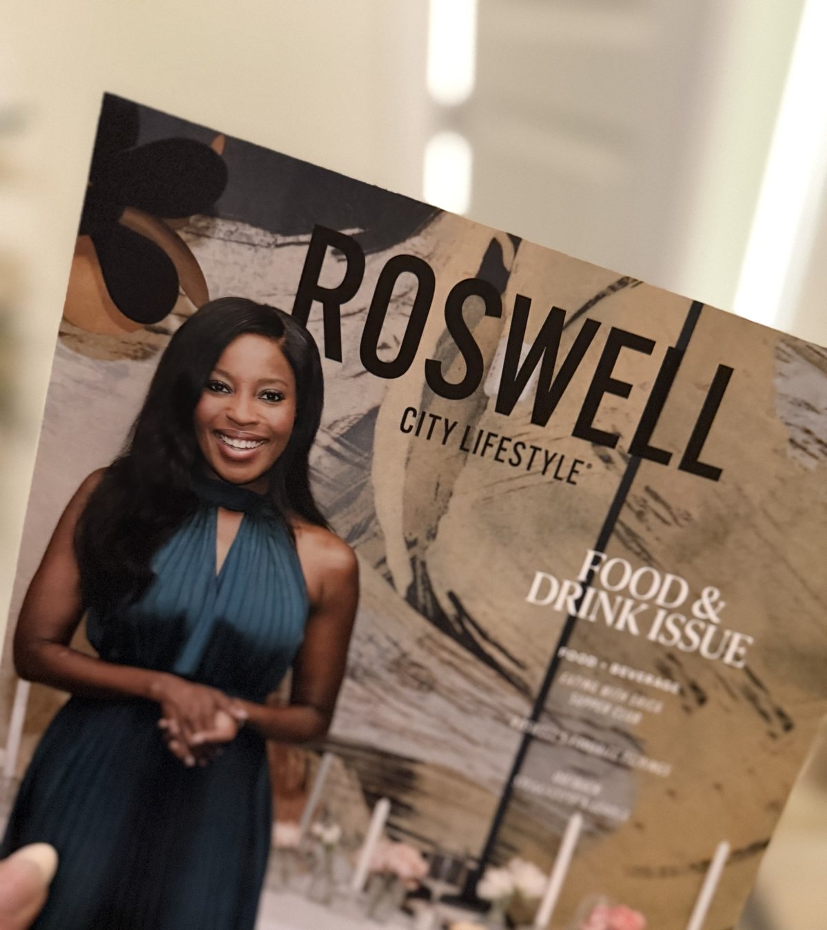 Erica A. Thomas smiling in a teal pleated halter dress on the cover of the Roswell City Lifestyle Food and Drink Issue