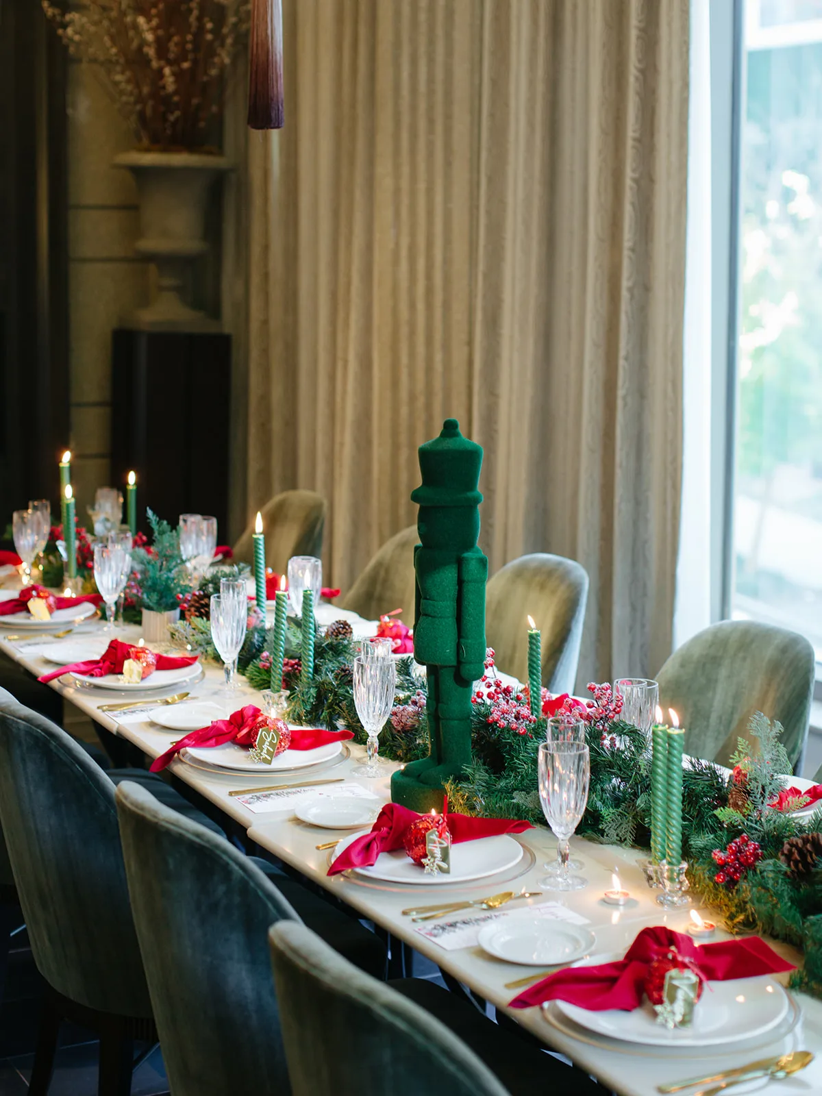 Holiday dinner table with a green nutcracker centerpiece, pinecones, berries and candlelight in a private dining room