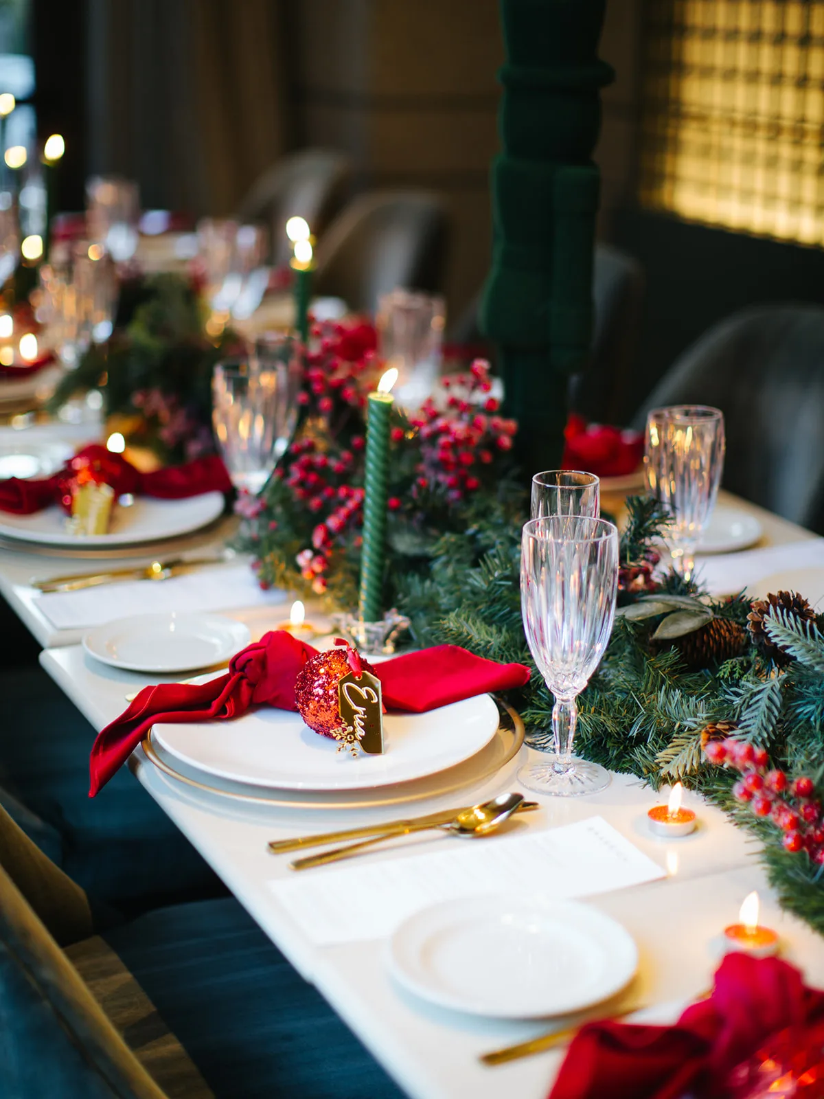 Close-up of a gold Erica place card on a red glitter ornament with a red velvet napkin and crystal flute