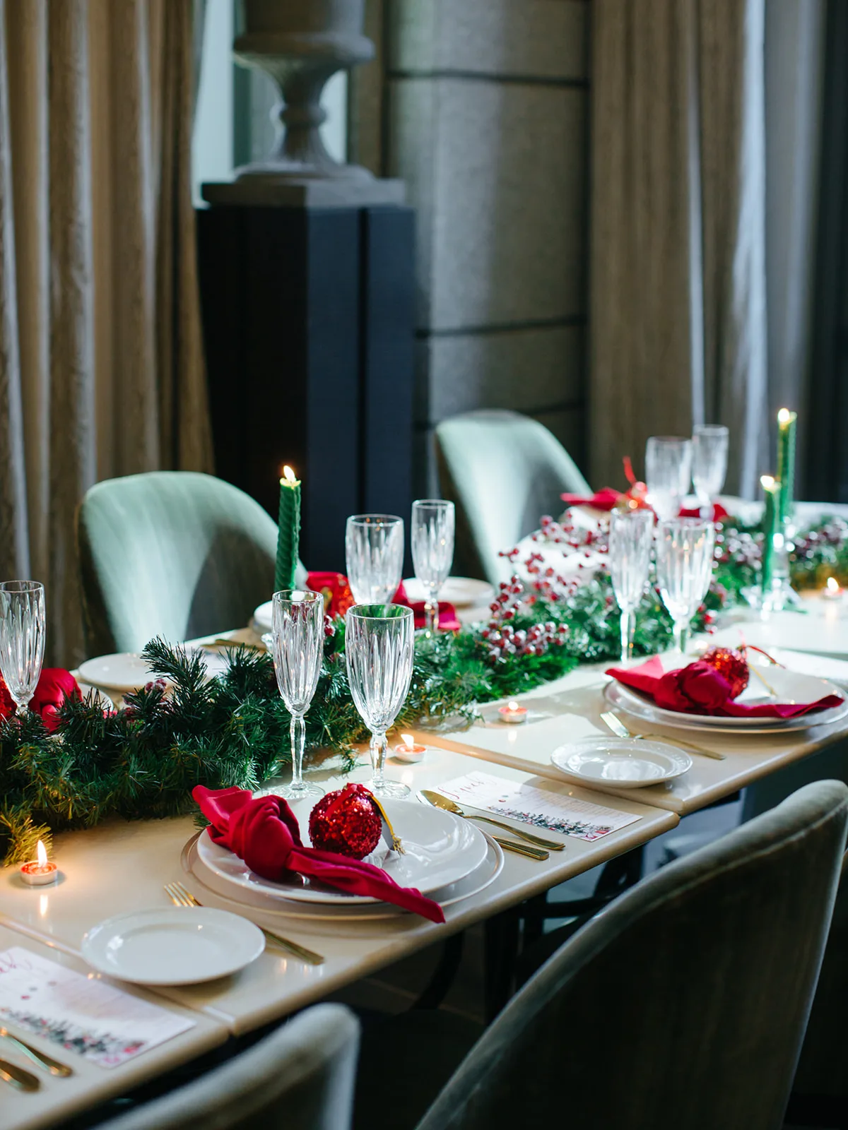 Holiday place settings with crystal champagne flutes, red velvet napkins and a red glitter ornament on white plates