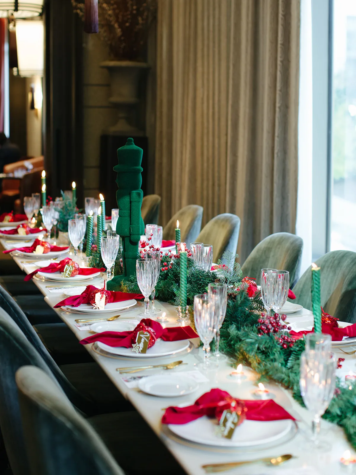 Holiday tablescape with a green flocked nutcracker, twisted green taper candles, crystal glassware and red velvet napkins